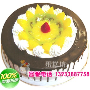 圆形鲜奶水果蛋糕，中间时令水果，周边巧克力酱装饰。
